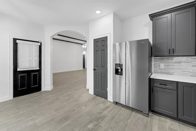 kitchen featuring beamed ceiling, ceiling fan, decorative backsplash, and stainless steel refrigerator with ice dispenser