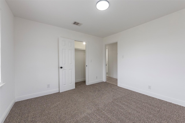 unfurnished bedroom featuring a walk in closet, carpet floors, and a closet