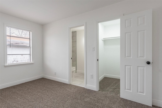 unfurnished bedroom featuring ensuite bath, a spacious closet, light carpet, and a closet