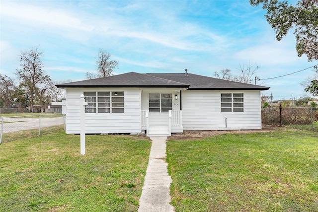 view of front of property with a shingled roof, fence, and a front lawn