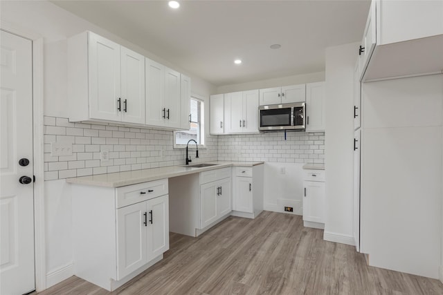 kitchen featuring decorative backsplash, white cabinetry, sink, and light wood-type flooring