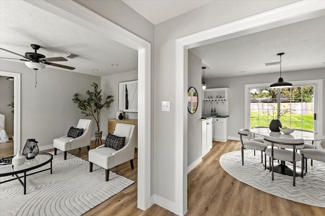 interior space featuring ceiling fan, a textured ceiling, and light hardwood / wood-style floors