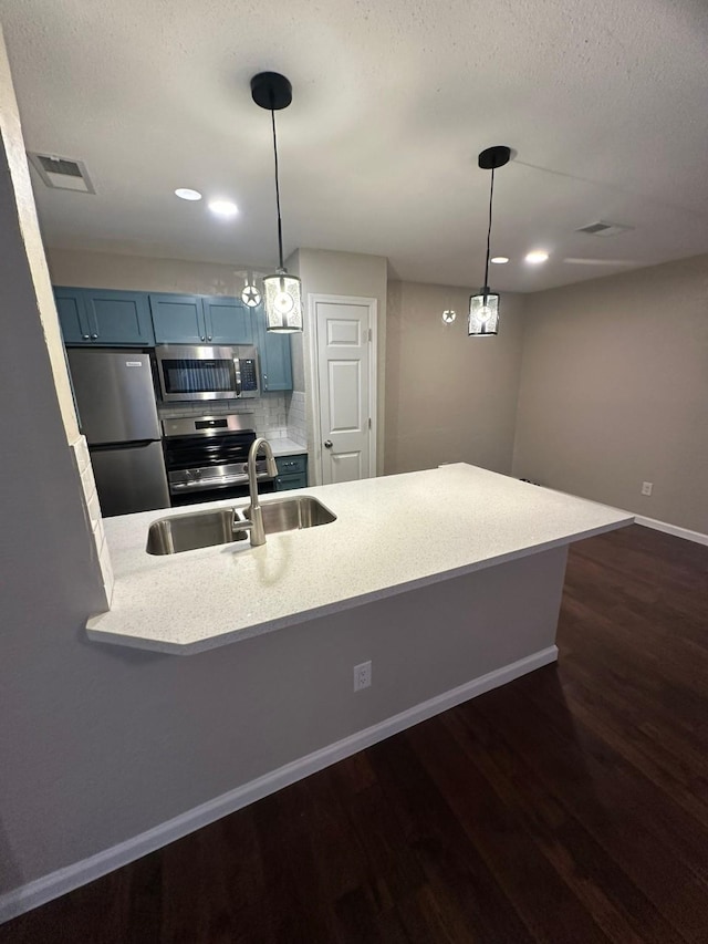 kitchen with hanging light fixtures, kitchen peninsula, blue cabinetry, and appliances with stainless steel finishes