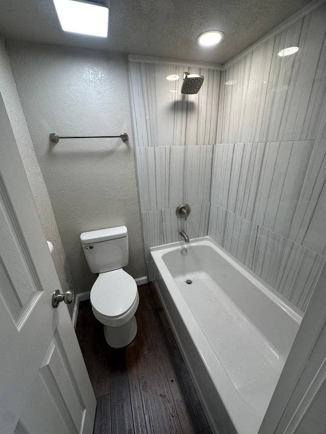 bathroom with hardwood / wood-style floors, toilet, shower / tub combination, and a textured ceiling