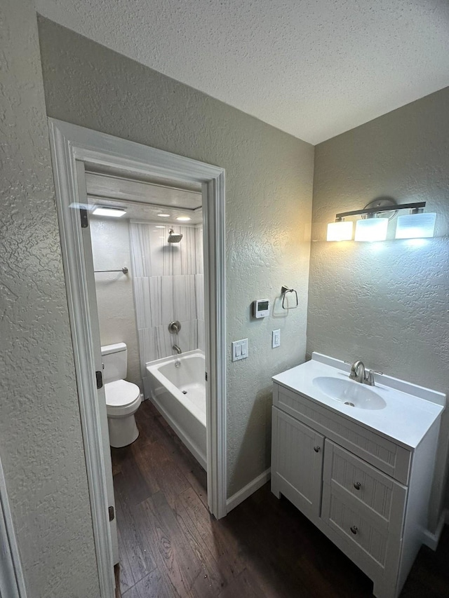 full bathroom featuring shower / bathing tub combination, wood-type flooring, a textured ceiling, toilet, and vanity