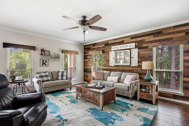 living room featuring ornamental molding, ceiling fan, wooden walls, and wood-type flooring