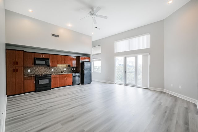 kitchen with black appliances, ceiling fan, light hardwood / wood-style floors, and a high ceiling