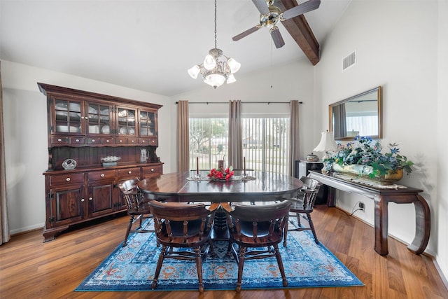 dining space featuring lofted ceiling with beams, ceiling fan with notable chandelier, and light hardwood / wood-style floors