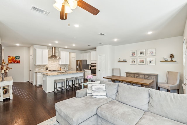 living room featuring ceiling fan, sink, and dark wood-type flooring