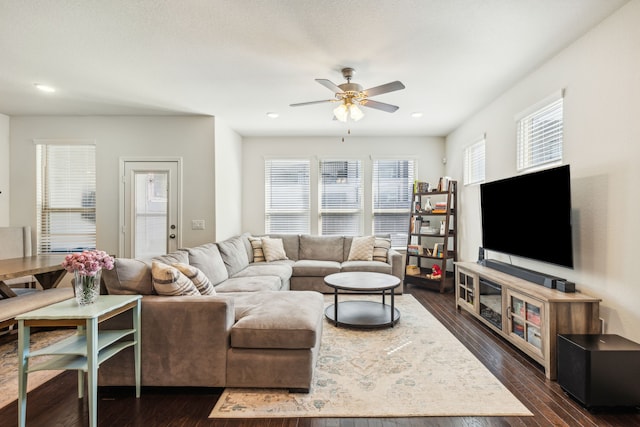 living room featuring a wealth of natural light, ceiling fan, and dark wood-type flooring