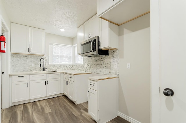 kitchen featuring backsplash, sink, white cabinets, and light hardwood / wood-style floors