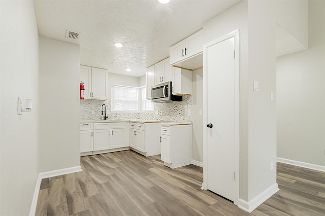 kitchen with white cabinetry, light hardwood / wood-style floors, sink, and tasteful backsplash