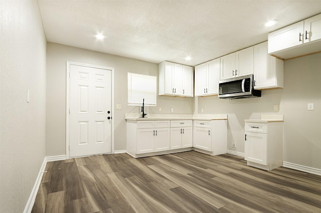 kitchen featuring hardwood / wood-style floors, white cabinets, and a textured ceiling