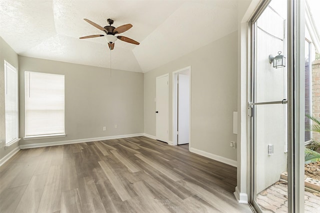 spare room featuring a textured ceiling, ceiling fan, wood-type flooring, and lofted ceiling