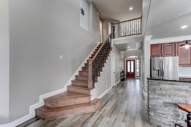 entrance foyer with ornamental molding, a textured ceiling, and light hardwood / wood-style flooring