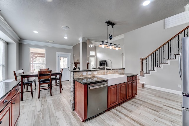 kitchen featuring sink, decorative light fixtures, a center island with sink, appliances with stainless steel finishes, and light wood-type flooring