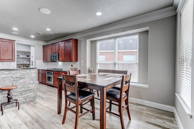 dining room with light wood-type flooring and ornamental molding