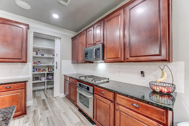 kitchen with dark stone countertops, decorative backsplash, light wood-type flooring, and appliances with stainless steel finishes