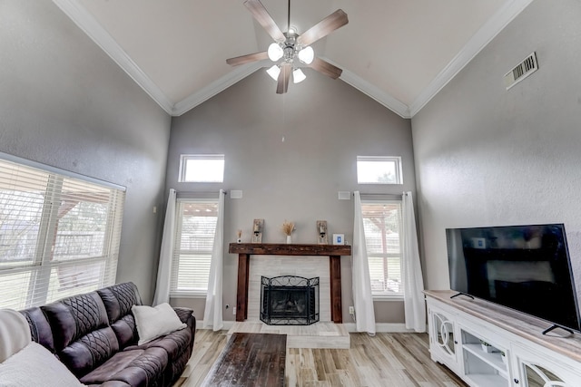 living room featuring ceiling fan, a fireplace, light wood-type flooring, and crown molding