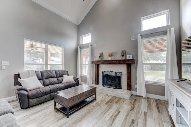 living room with a fireplace, crown molding, plenty of natural light, and light wood-type flooring