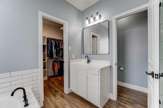 bathroom featuring a tub to relax in, decorative backsplash, hardwood / wood-style floors, and vanity