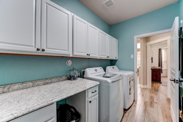 clothes washing area featuring light hardwood / wood-style floors, cabinets, and washing machine and clothes dryer