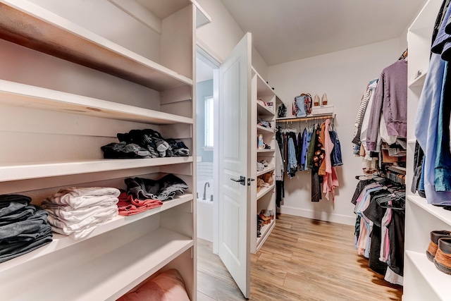 walk in closet with light hardwood / wood-style floors