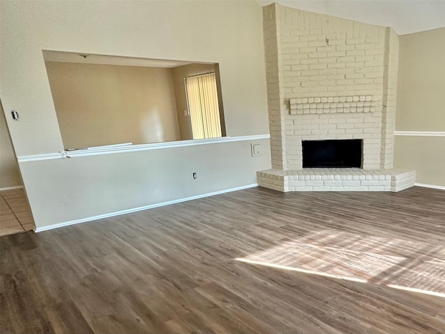 unfurnished living room featuring dark hardwood / wood-style flooring, a fireplace, and vaulted ceiling