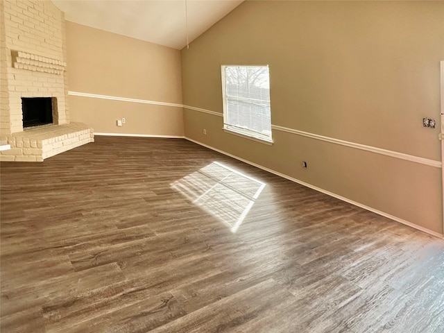 unfurnished living room featuring vaulted ceiling and a brick fireplace