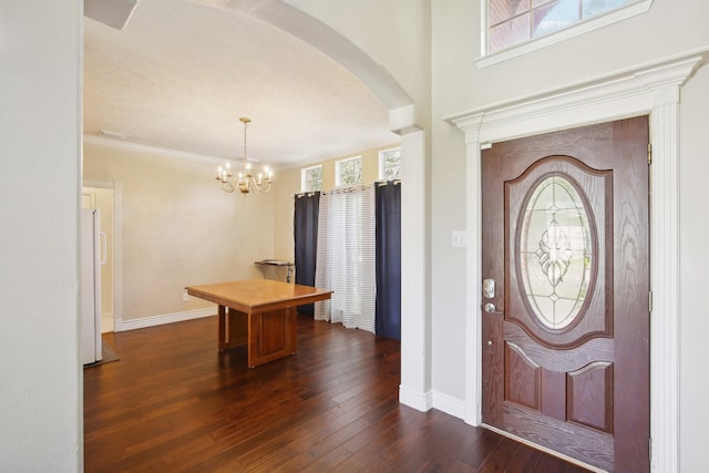 entrance foyer with dark hardwood / wood-style flooring, ornamental molding, and a notable chandelier