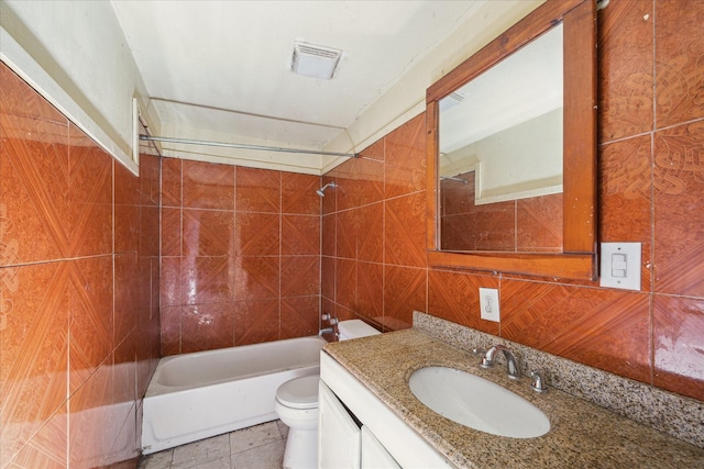 full bathroom with tiled shower / bath combo, tile patterned floors, toilet, vanity, and tile walls