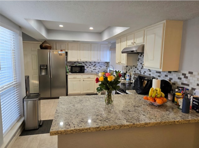 kitchen featuring kitchen peninsula, appliances with stainless steel finishes, a textured ceiling, and light tile patterned floors