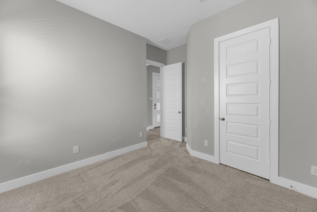 unfurnished bedroom with a closet and light colored carpet