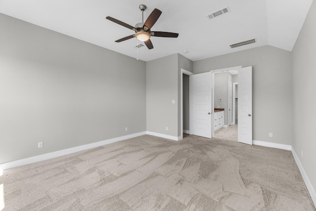 unfurnished bedroom with ceiling fan, ensuite bathroom, light carpet, and vaulted ceiling