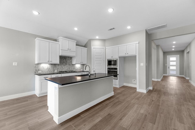 kitchen with white cabinets, appliances with stainless steel finishes, sink, and an island with sink