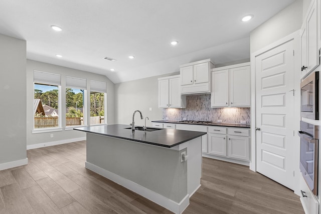 kitchen with backsplash, sink, white cabinets, and lofted ceiling