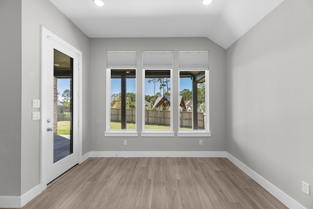 spare room featuring light hardwood / wood-style flooring and vaulted ceiling