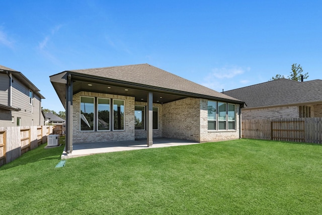 rear view of house with cooling unit, a patio area, and a yard