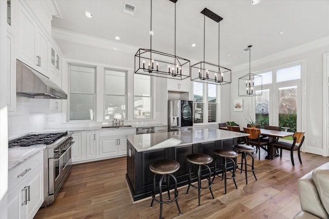 kitchen with white cabinetry, sink, decorative light fixtures, a kitchen island, and appliances with stainless steel finishes