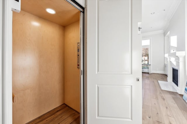 interior space featuring light wood-type flooring, ornamental molding, and elevator