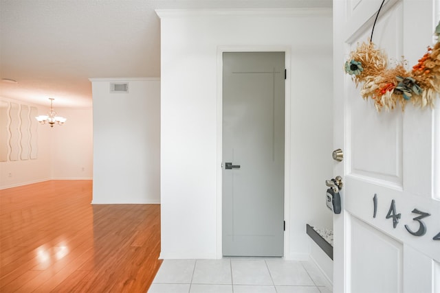 interior space with a notable chandelier, crown molding, and light tile patterned flooring