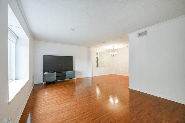 unfurnished living room featuring ornamental molding, hardwood / wood-style flooring, and a notable chandelier