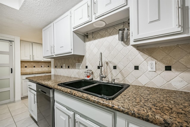 kitchen with white cabinetry, sink, light tile patterned floors, and stainless steel dishwasher