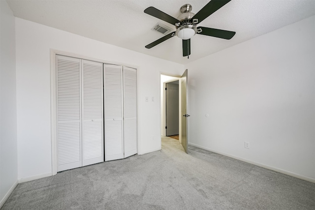 unfurnished bedroom with ceiling fan, light colored carpet, and a closet