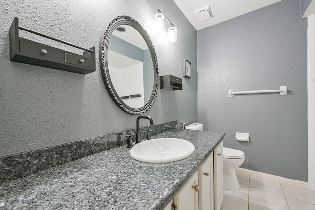 bathroom with toilet, vanity, and tile patterned floors