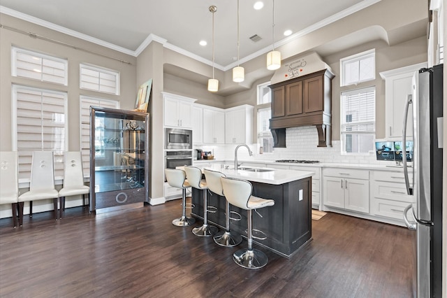 kitchen with appliances with stainless steel finishes, sink, white cabinetry, and an island with sink