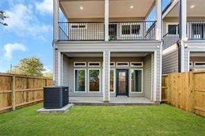 back of property featuring a balcony, central AC, a patio area, and a lawn