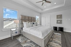 bedroom featuring ceiling fan, dark hardwood / wood-style flooring, and a tray ceiling