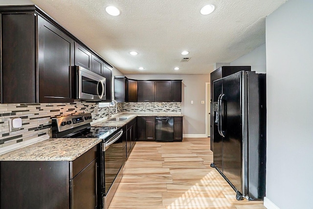 kitchen featuring backsplash, light stone counters, sink, and black appliances