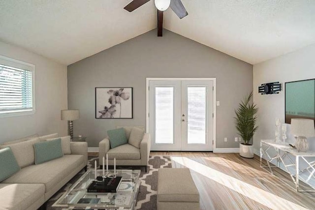 living room featuring vaulted ceiling with beams, light hardwood / wood-style floors, a wealth of natural light, and french doors